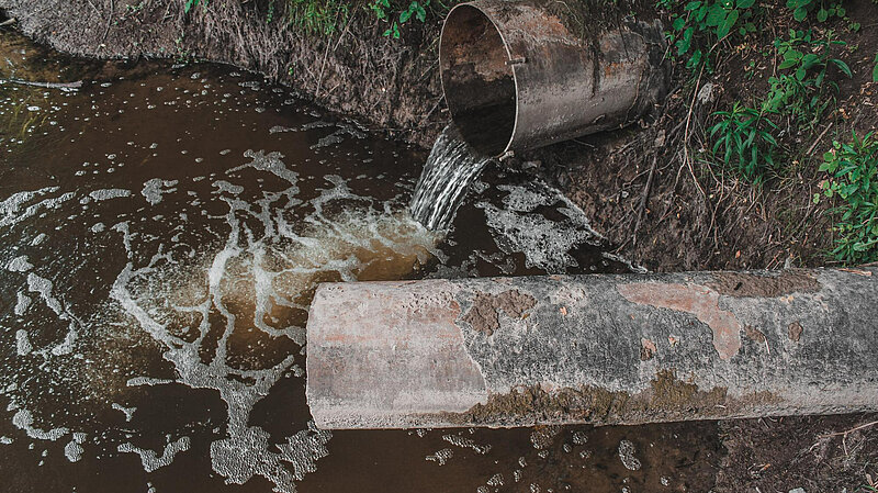 Dirty water pouring from pipe into water course